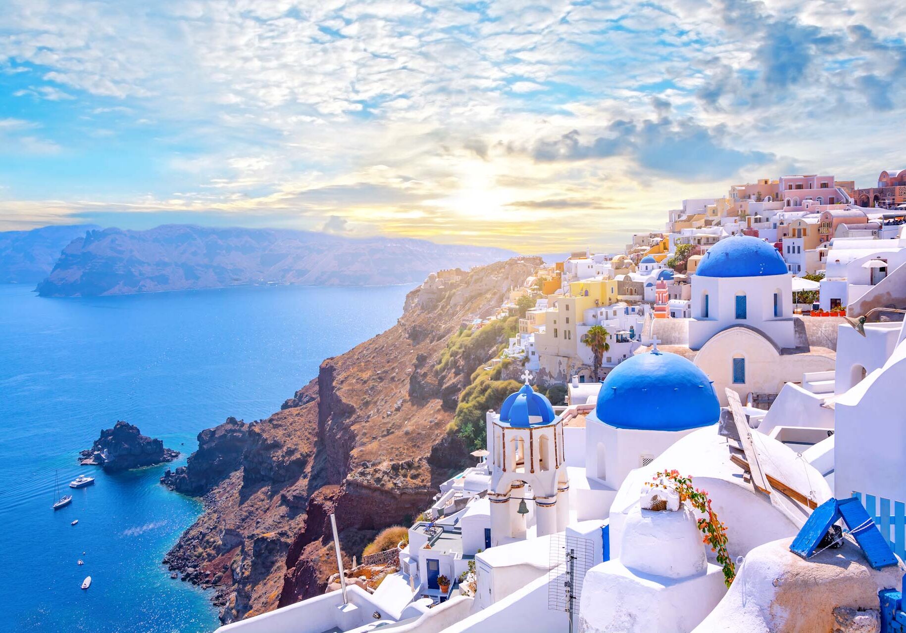 Beautiful Oia town on Santorini island, Greece. Traditional white architecture  and greek orthodox churches with blue domes over the Caldera, Aegean sea. Scenic travel background.