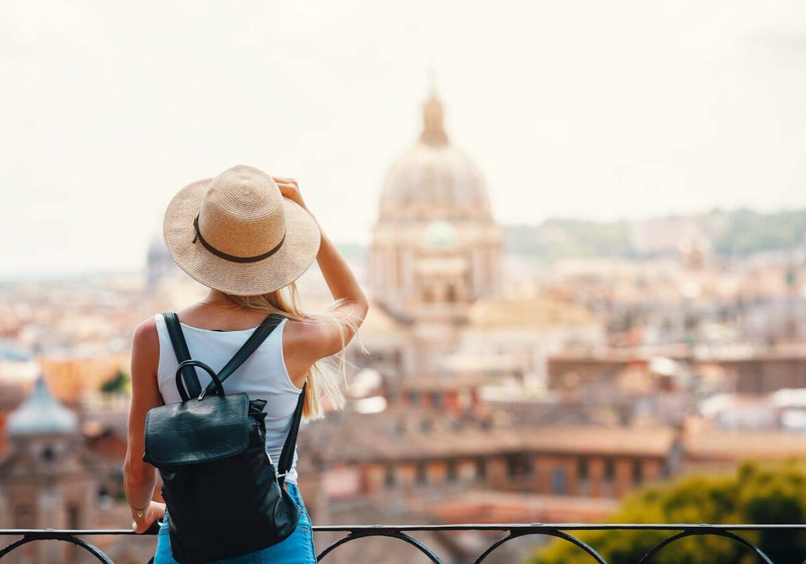 Young attractive smiling girl tourist exploring new city at summer